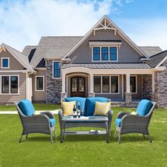 an outdoor living area with furniture in front of a large, well - manicured house