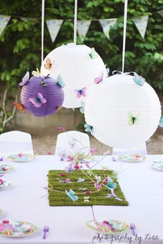 some paper lanterns hanging from the ceiling above a table with plates and napkins on it