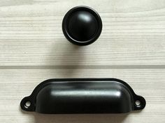 two black knobs on a wooden cabinet