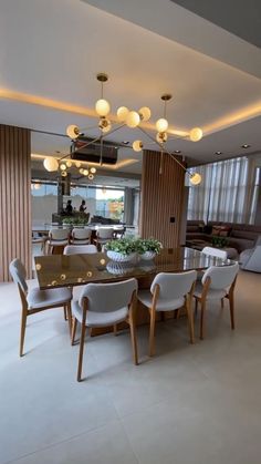 the dining room table is surrounded by white chairs and modern lighting fixtures in an open space