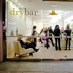 a group of people standing in front of a store window that says drybar on it