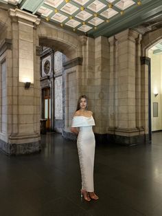 a woman in a white dress posing for a photo inside an ornately decorated building