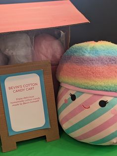 a colorful stuffed animal next to a box of cotton balls and a sign that says bevin's cotton candy