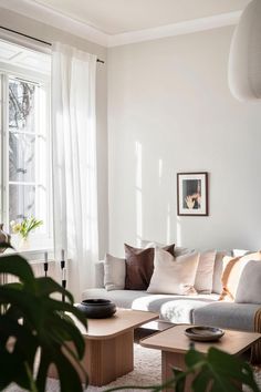 a living room filled with lots of furniture next to a large window covered in white curtains