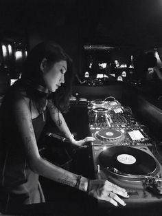 a woman that is sitting at a dj's turntable in front of a record player