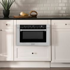 a kitchen with white cabinets and black counter tops, an oven built into the wall