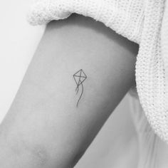 a small kite tattoo on the left inner forearm and arm, it is black and white