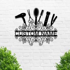 a metal sign that says custom name with scissors and hairdryers on it in front of a white brick wall