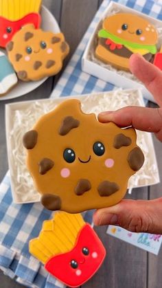 a person holding up a cookie shaped like a hamburger and burger on it's side