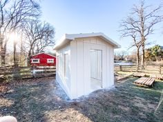 a small white shed sitting in the middle of a field