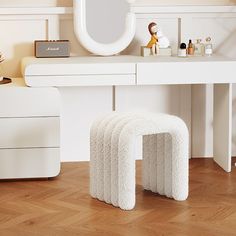 a white vanity with four stools and a mirror on the wall above it in a room