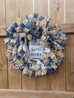 a blue and white wreath with the words home sweet home on it hanging on a wooden fence