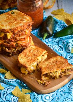 two grilled cheese sandwiches on a cutting board with chips and salsa in the background