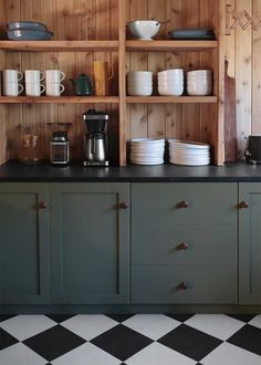 a kitchen with black and white checkered flooring, shelves filled with dishes and cups