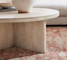 a white vase sitting on top of a wooden table in a living room next to a couch