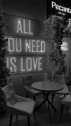 an all you need is love neon sign on the wall in front of a restaurant