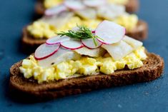 toasted bread topped with eggs, radishes and other toppings on a blue surface