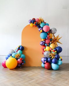 an arch made out of balloons and stars on the floor next to a wooden floor