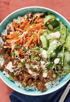 a bowl filled with rice, meat and veggies next to chopsticks