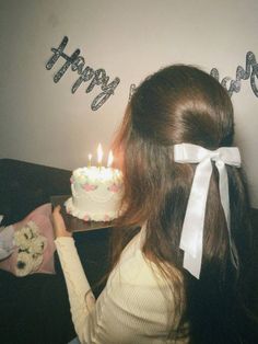 a woman holding a birthday cake with candles on it and the words happy birthday spelled out in silver letters