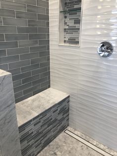 a walk in shower sitting next to a tiled wall