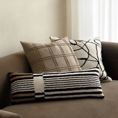 three pillows on a couch in front of a window