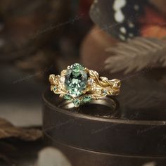 a ring with a green stone surrounded by leaves