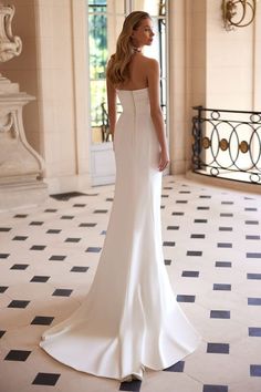 a woman in a white wedding dress looking off into the distance with her back to the camera