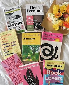 there are many books on the bed with flowers in front of them and an envelope