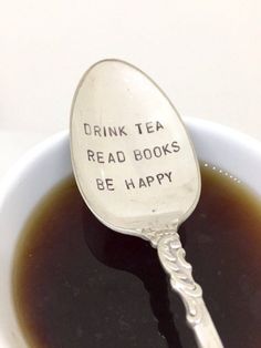 a spoon that has some kind of tea on it with the words drink tea read books be happy