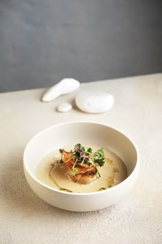 a white bowl filled with food sitting on top of a table next to spoons