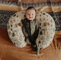 a baby laying on top of a pillow in the shape of a circle with bugs around it