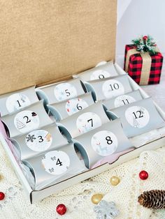 the twelve days of christmas cards are in a gift box next to a pine cone