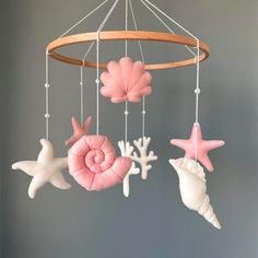 a pink and white mobile with sea shells, stars and seashells hanging from it