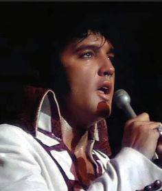 elvis presley singing into a microphone with his hands in his pockets