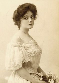 an old photo of a woman in a dress with flowers on her head and shoulders