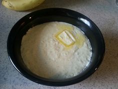 a black bowl filled with batter next to a banana on top of a white counter