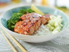 salmon and broccoli in a bowl with chopsticks next to it on a table