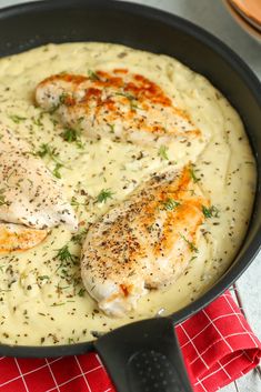 some chicken is cooking in a skillet on a red and white checkered cloth