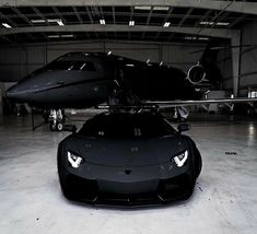 a black sports car parked in front of an airplane