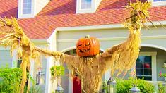 a scarecrow in front of a house with a pumpkin on it's head