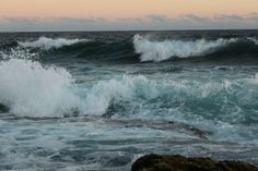 the waves are crashing on the rocks in the ocean