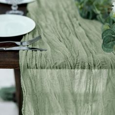 the table is set with plates, silverware and green linens for an elegant look