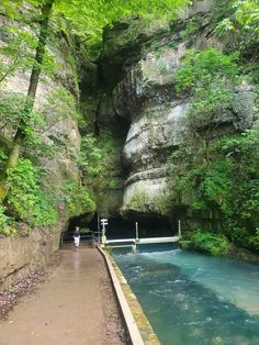 a man is standing at the end of a tunnel in a river with blue water