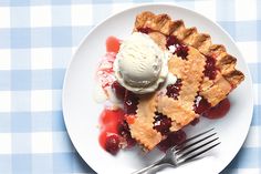 a piece of pie on a plate with ice cream and cherry sauce next to it