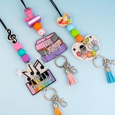 four key chains with different designs and colors on them, one has a bag charm attached to it