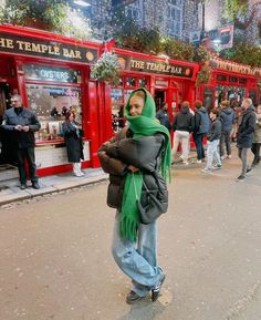 a woman with a green scarf on her head is standing in front of a store