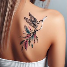 the back of a woman's shoulder with a bird and feathers tattoo on it