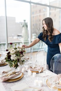 a woman setting a table with plates and place settings