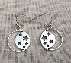 These are so cool and unique!  Silver discs with cutout stars and moon design.  They are eye catching and versatile.  The perfect everyday earrings for any star and moon lover.The earrings measure 5/8” long by 5/8” wide and hang from simple silver ear wire hooks.  Overall drop length is 3/4”.  Made from allergy free plated silver.I have a matching necklace in my shop, if you would like the whole set.  Here is the link......... https://etsy.me/2KOGpkx Thanks for stopping by!  Please take a moment Moon Phase Star Earrings For Gift, Nickel-free Star Shaped Symbolic Earrings, Symbolic Star-shaped Nickel-free Earrings, Symbolic Nickel-free Star Earrings, Silver Moon Earrings, Cricut Jewelry, Moon Lover, Bubble Earrings, Celestial Earrings